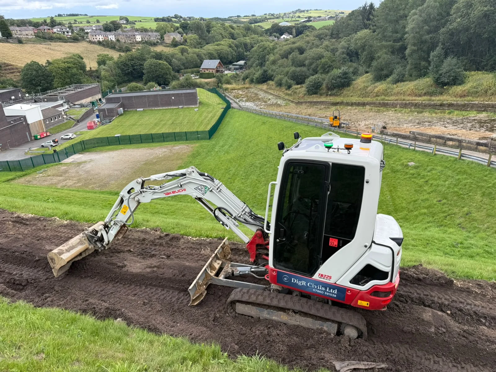 DigR Civils Takeuchi excavator grading a hillside above a waterworks valley